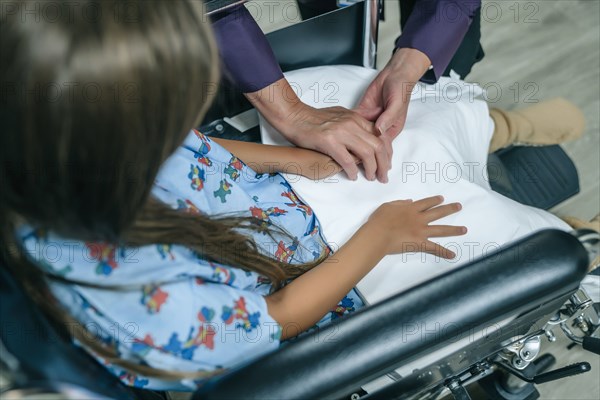 Doctor holding hands with girl in a wheelchair