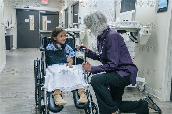 Doctor talking to girl in a wheelchair