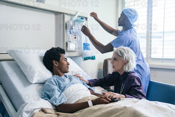 Doctor comforting boy laying in hospital bed