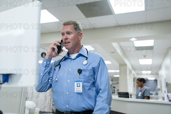 Doctor using computer and talking on cell phone