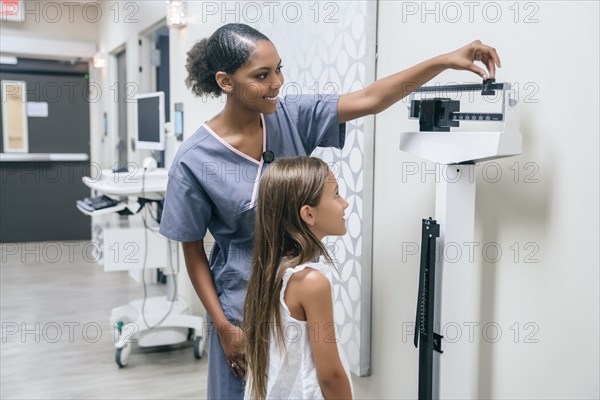 Nurse weighing girl on scale