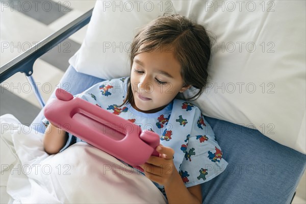 Mixed race girl using digital tablet in hospital bed