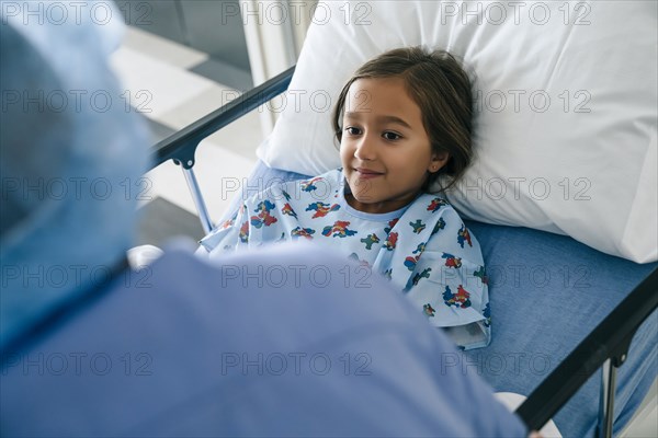 Nurse talking to girl in hospital bed