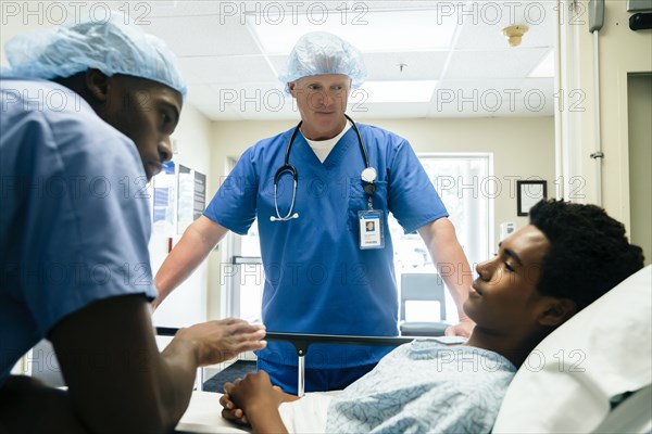 Nurses talking to boy in hospital bed