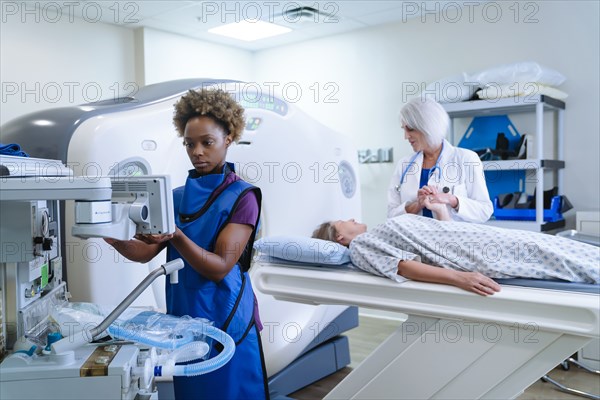 Technician preparing scanner for doctor comforting patient