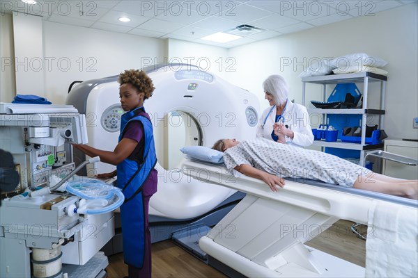 Technician preparing scanner for doctor comforting patient