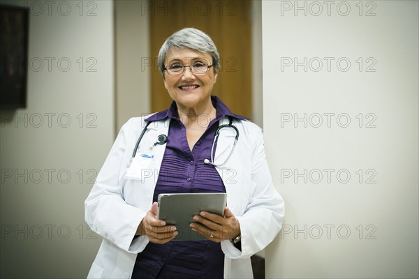 Portrait of smiling mixed race doctor using digital tablet