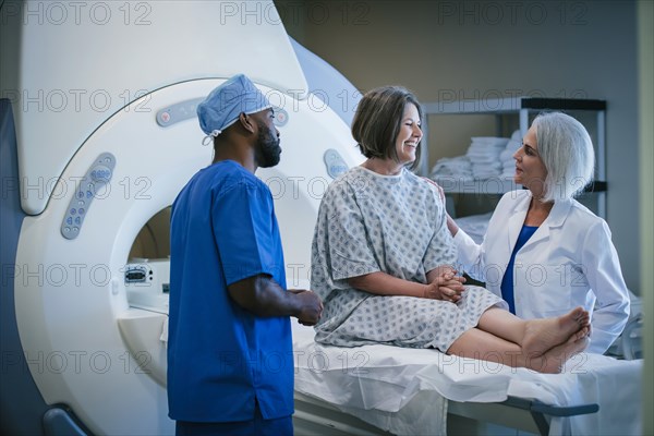 Doctor and technician talking to patient at scanner