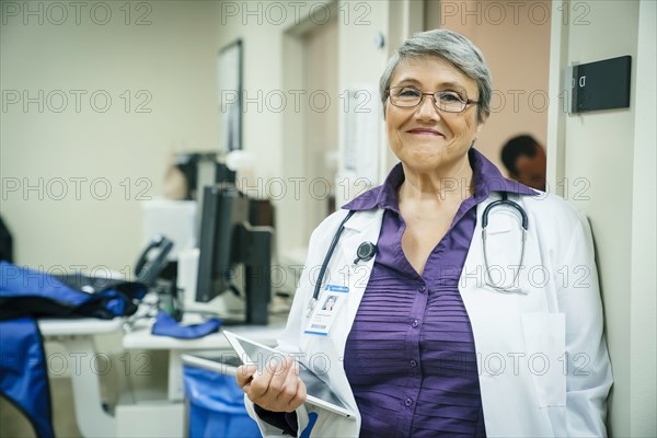 Portrait of smiling mixed race doctor holding digital tablet