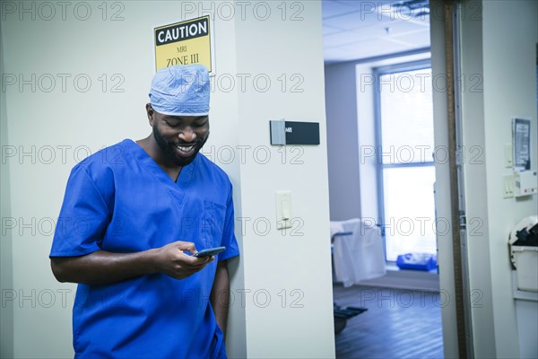 Smiling black nurse texting on cell phone