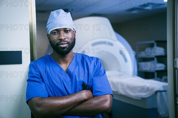 Portrait of confident black nurse near scanner