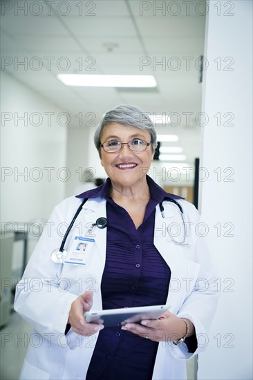 Smiling mixed race doctor holding digital tablet