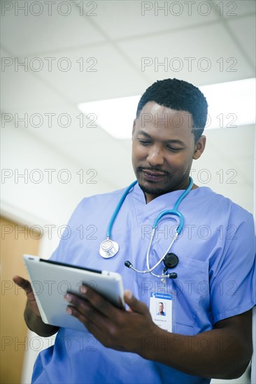 Black nurse using digital tablet in hospital