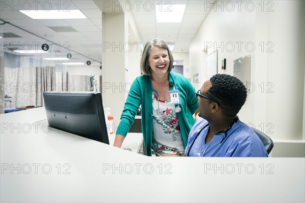 Doctor and nurse laughing near computer