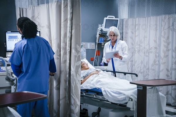 Doctor with digital tablet talking to patient in hospital bed