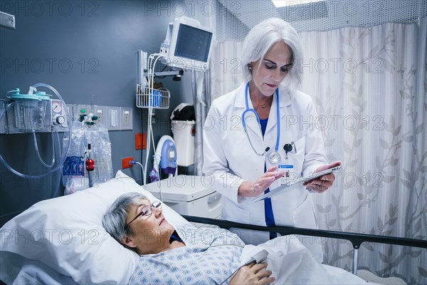 Doctor with digital tablet talking to patient