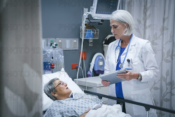 Doctor with digital tablet talking to patient