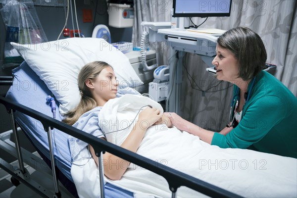 Caucasian doctor comforting patient in hospital bed