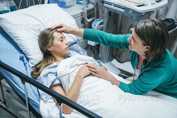 Caucasian doctor comforting patient in hospital bed