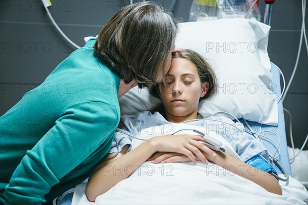 Caucasian mother kissing your daughter on forehead in hospital