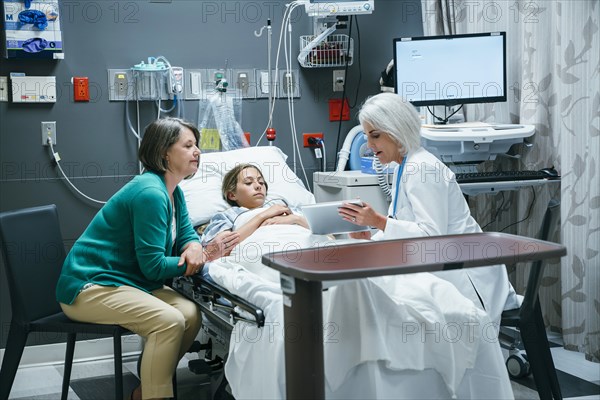 Caucasian doctor with digital tablet talking to mother and daughter in hospital