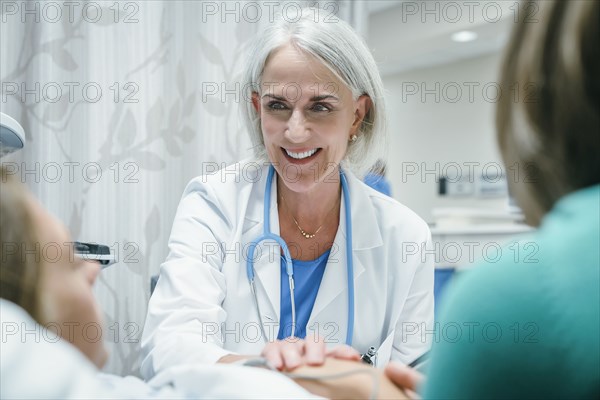 Caucasian doctor comforting girl in hospital bed