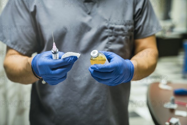 Mixed race nurse wearing rubber-gloves holding medicine and needle