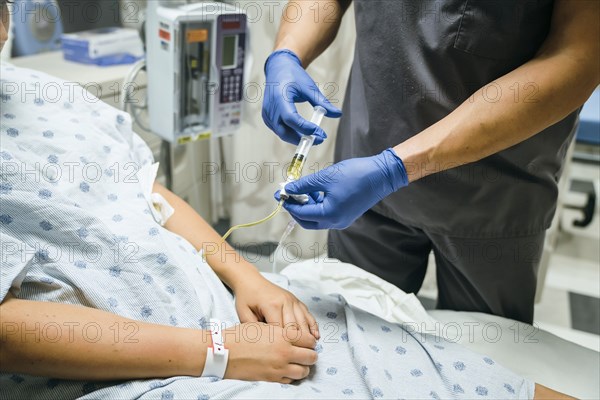 Nurse injecting medicine into tube of patient