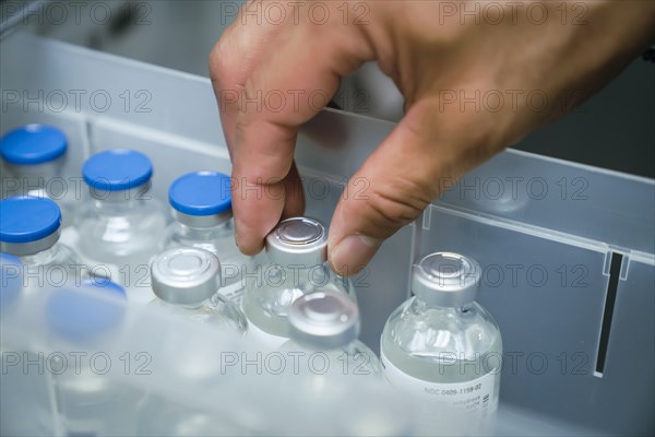 Hand of mixed race person holding vial of medicine