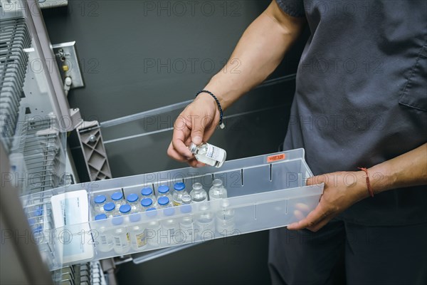 Mixed race nurse examining vial of medicine