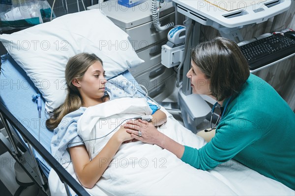 Doctor comforting Caucasian girl laying in hospital bed