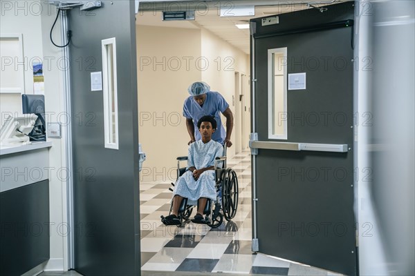 Black nurse pushing boy in wheelchair