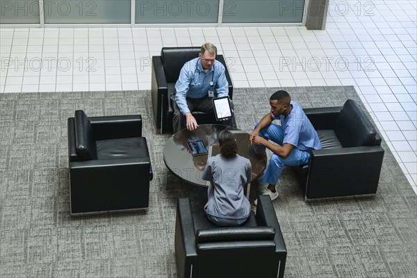 Doctor holding digital tablet talking to nurses in lobby