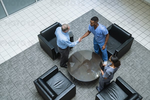 Doctor and nurse shaking hands in lobby