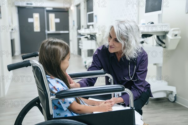 Smiling doctor talking to girl in wheelchair