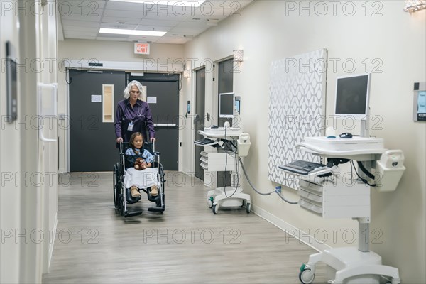 Doctor pushing girl in wheelchair