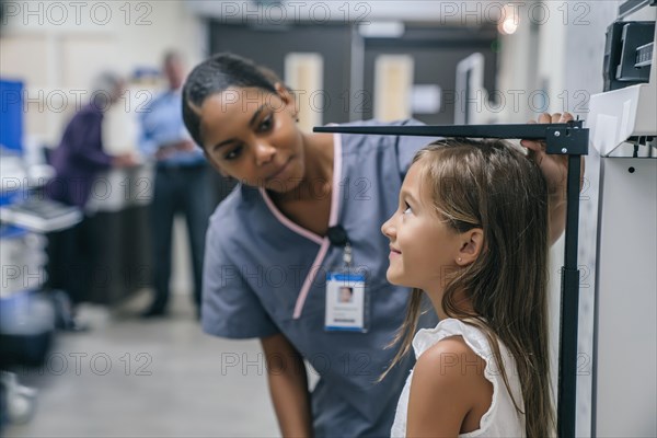 Nurse measuring height of girl in hospital