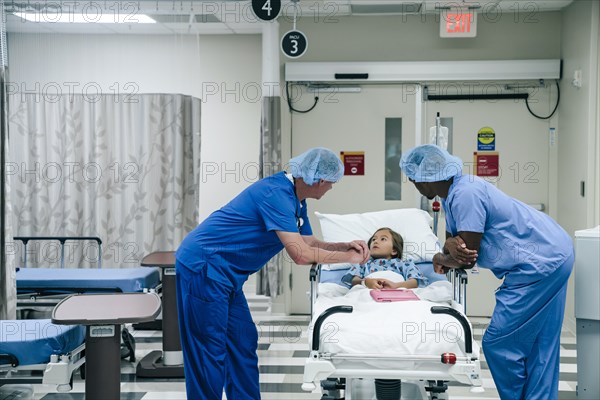 Doctors talking to girl in hospital gurney