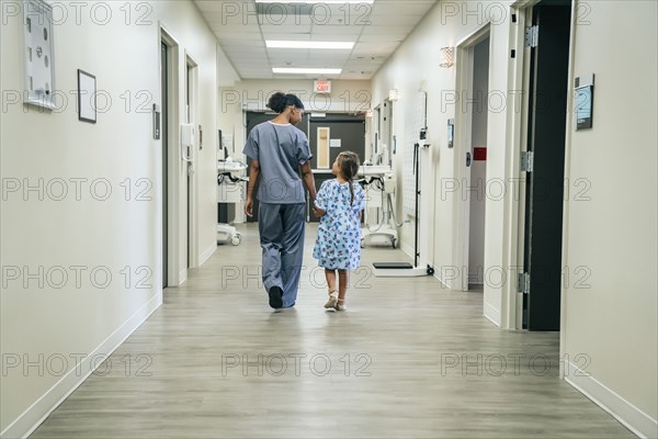 Nurse walking with girl in hospital corridor