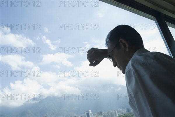 Hispanic businessman looking out window