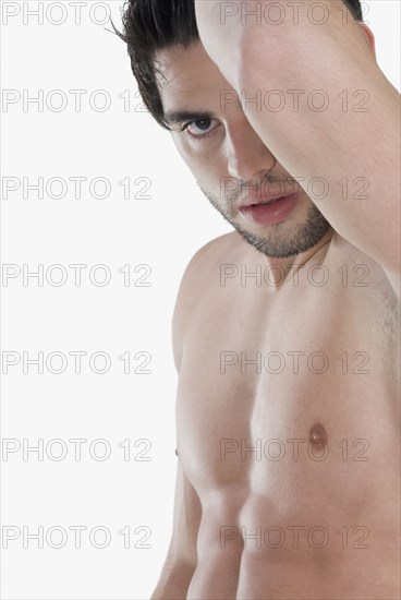 Bare-chested Hispanic man holding arm up
