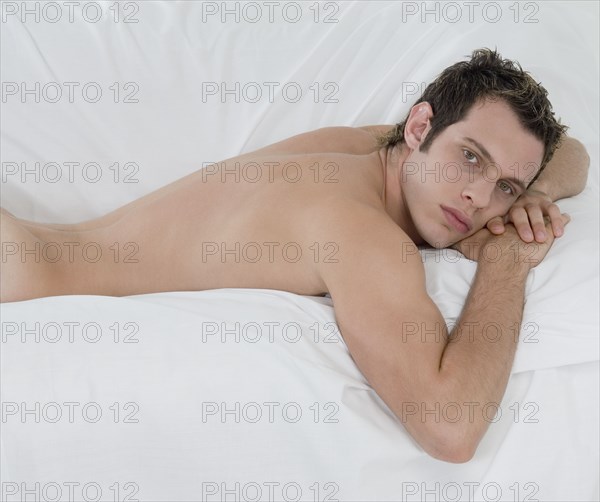 Nude man laying on bed