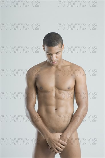 Nude African man with hands over groin