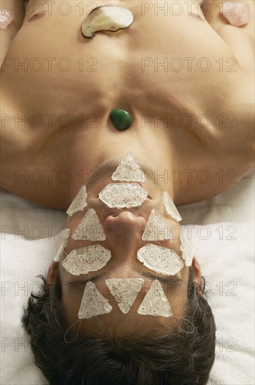 Hispanic man receiving stone and crystal spa treatment