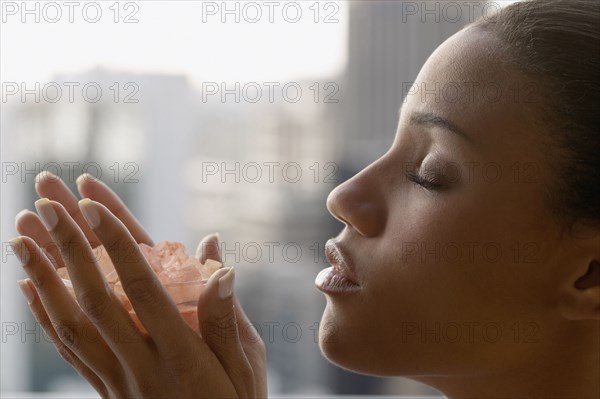 African woman with eyes closed holding bowl of crystals