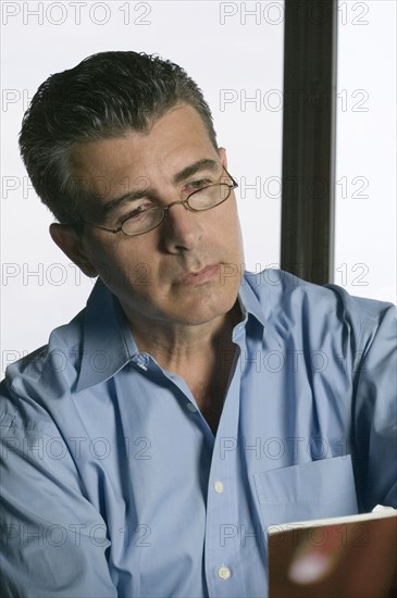 Studio shot of Hispanic middle-aged man reading