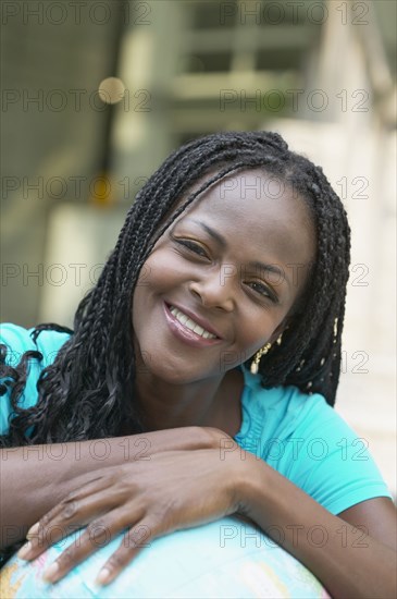 African woman leaning on globe