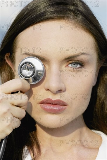 Close up of woman holding stethoscope over eye