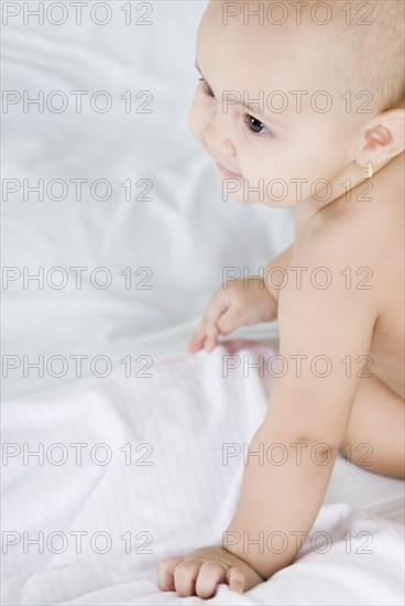 Hispanic baby sitting on bed