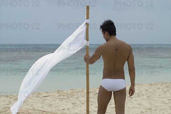 Hispanic man holding flag at beach